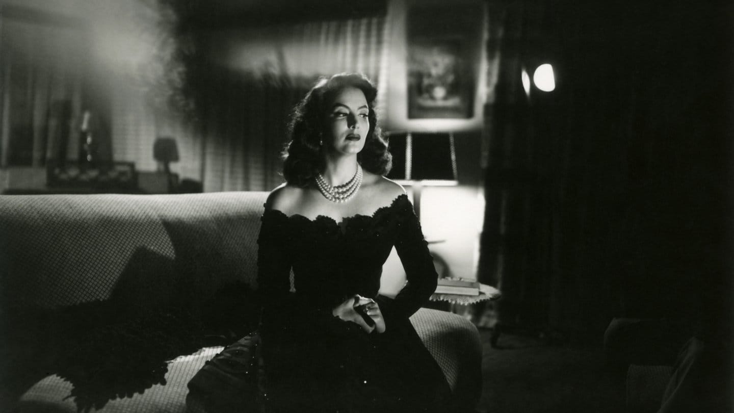 María Felix, la doña, vestida de negro y sentada en un sofá