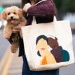 mujer sostiene a perro color cafe con el brazo derecho y una bolsa de tela cuelga de su hombro izquierdo