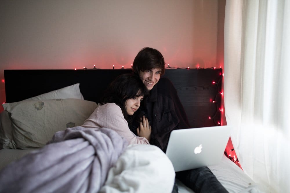pareja mirando peliculas en su cama