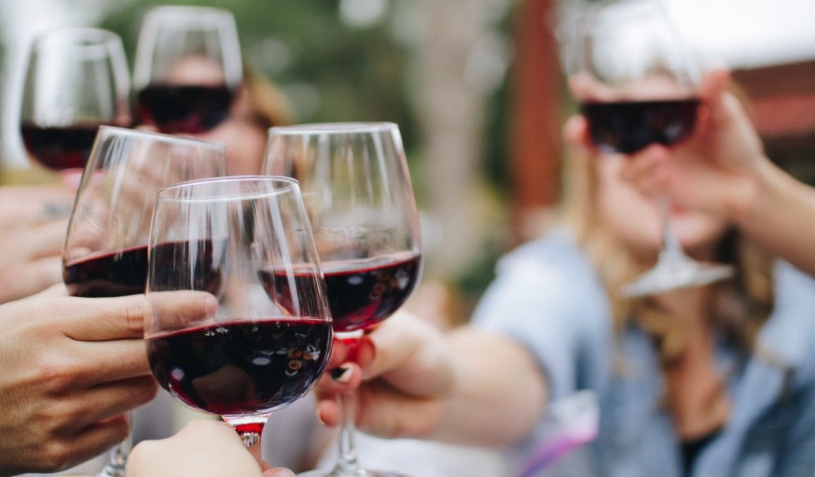 personas brindando con copas de vino tinto