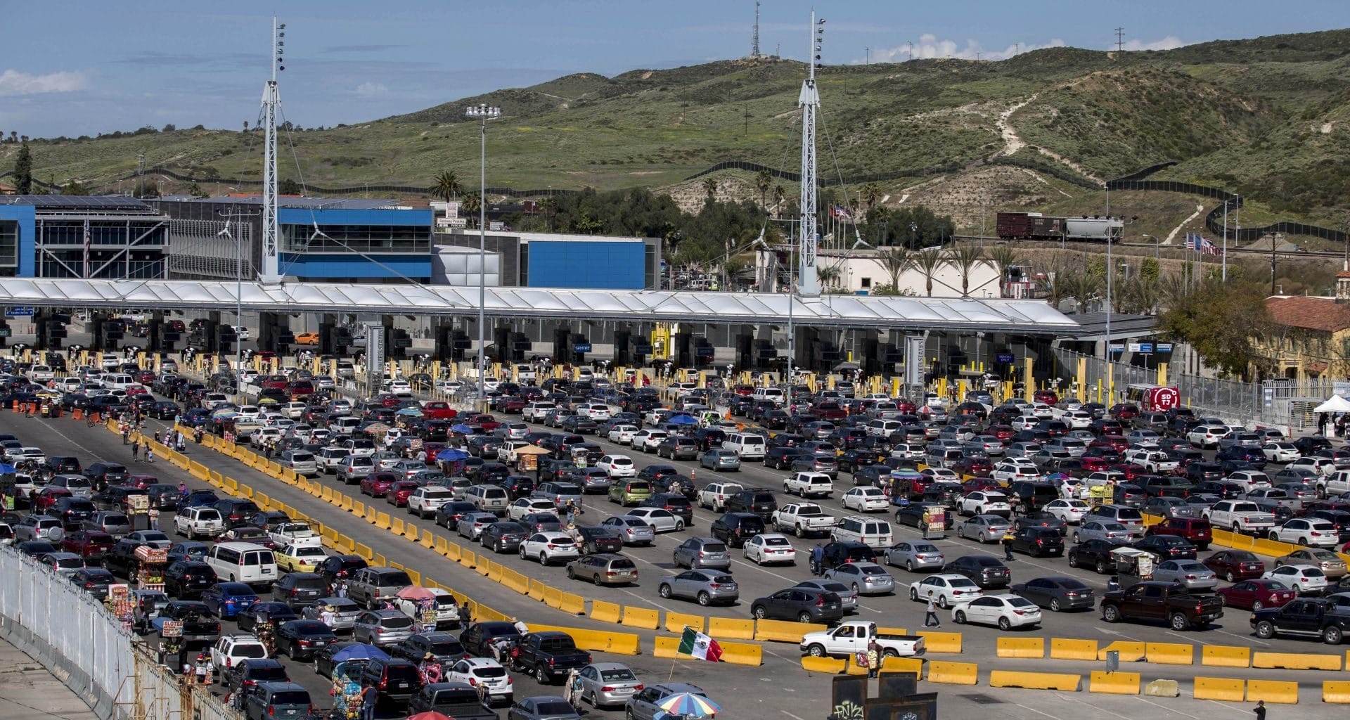 Linea de la frontera de Tijuana. En medio hay una línea color amarillo fuerte y por los dos lados se encuentran diversidad de carros