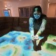 mujer sostiene arena entre sus manos dentro de un museo