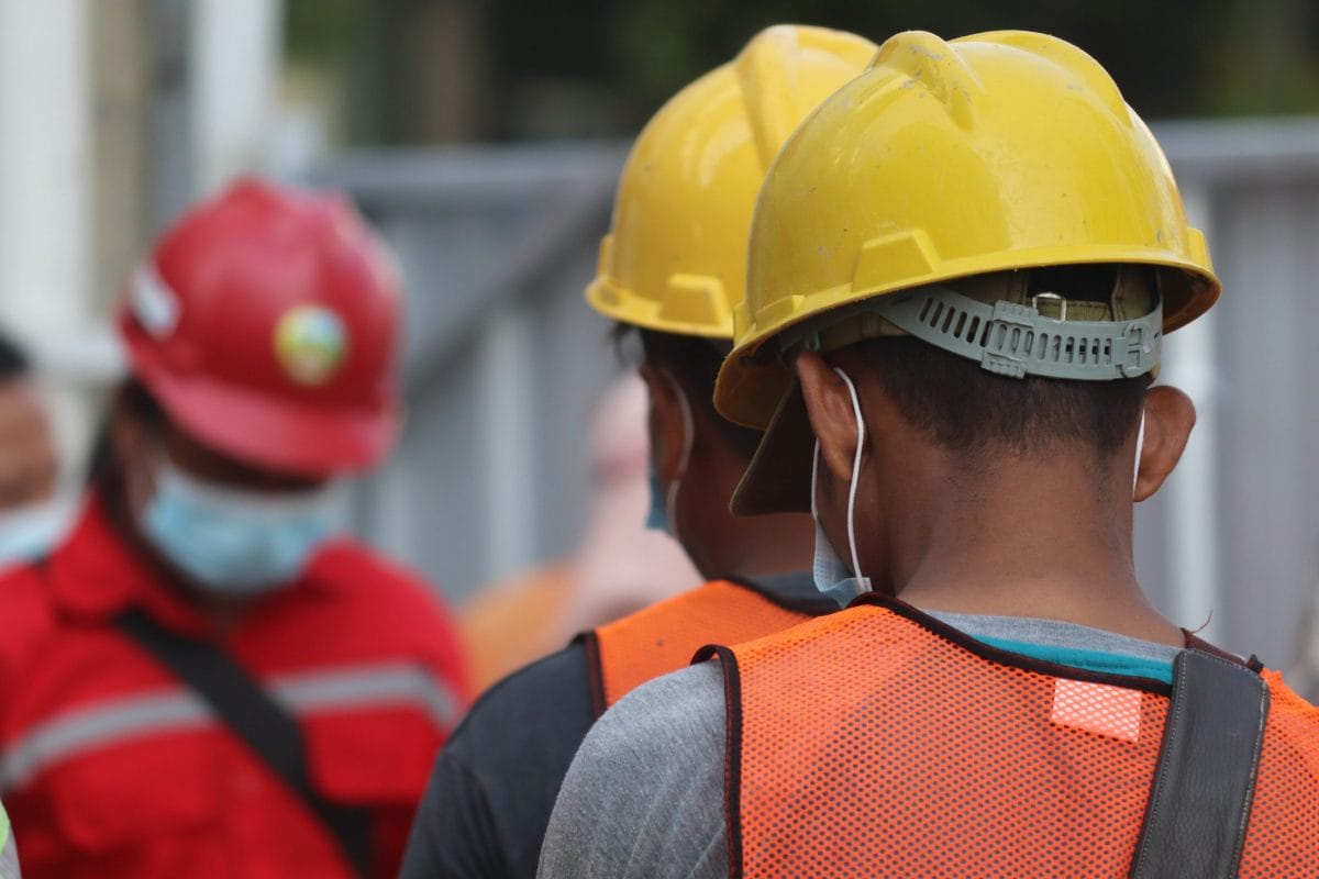 Trabajadores de espalda con cascos de construcción. 