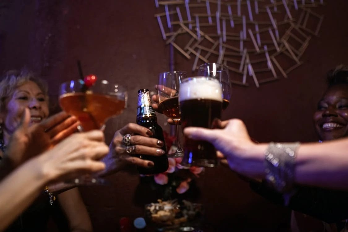 Un grupo de personas brindan con cervezas y cócteles.
