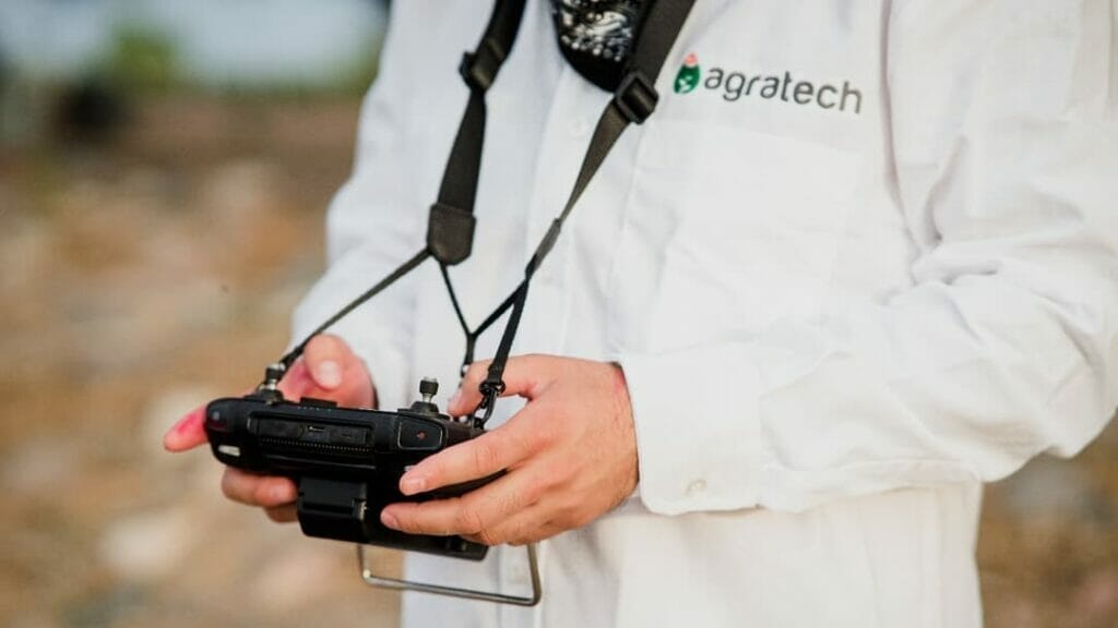 hombre con uniforme de agratech con controlador de dron en las manos